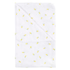 Die KraftKids Babydecke Musselin gelbe Zitronen ist eine weiße Decke mit einem Muster aus kleinen gelben Zitronen und grünen Blättern, die fein säuberlich gefaltet ist.
