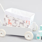 Auf einem weißen Spielzeugwagen steht das KraftKids Körbchen kleine Rehkitze grau orange auf Weiß, verziert mit Hirschen, neben gestapelten pastellfarbenen Blöcken mit Zahlen und Mustern auf hellgrauem Hintergrund.