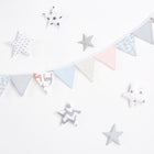 Die pastellfarbene Wimpelkette "Wimpelkette kleine Blätter und kleine Rehkitze" von KraftKids hängt diagonal vor einem weißen Hintergrund, umgeben von zarten Stoffsternen in Grau, Weiß und Pastell - ein charmantes Kinderzimmer-Deko.