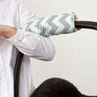 Eine Person schiebt einen Kinderwagen mit einer KraftKids Armschoner Babyschale in hellgrau und mintfarbenem Chevron, die mit einem praktischen Klettverschluss versehen ist. Nur der Arm und ein Teil des weißen Hemdes sind zu sehen.