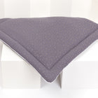 Die KraftKids Wickelauflage Musselin goldene Punkte auf Grau, eine dunkelgraue, dreieckige, gesteppte Wickelauflage mit kleinen goldenen Punkten, ist auf drei weißen Würfeln auf weißem Hintergrund abgebildet.