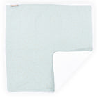 Eine grüne, L-förmige Wickelunterlage Musselin mit goldenen Punkten von KraftKids ist flach auf einem weißen Hintergrund abgebildet. Eine Ecke ist umgeschlagen, so dass ein weißes Innenfutter zum Vorschein kommt.