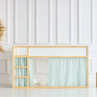 Ein modernes Kinderhochbett im Stil von IKEA Kura ist das KraftKids Hochbettvorhänge Set 2+1 Musselin mit goldenen Punkten auf Grün. Vor einer weiß getäfelten Wand wird es von Pampasgras in einer Vase und zwei Würfelhockern aus Holz flankiert.