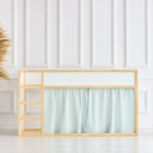 Ein minimalistisches Zimmer mit einem Kinderbett aus Holz, KraftKids Hochbettvorhänge Set 2+1 Musselin mint Pusteblumen für Kura Bett, einer großen geflochtenen Vase mit getrocknetem Pampasgras und zwei Holzhockern vor einer weiß getäfelten Wand und einem hellen Boden.