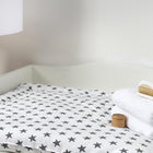 Eine KraftKids Wickelstation mit Sternchenmatte, weißen Handtüchern, Holzhaarbürste und Gläschen steht neben einer Stehlampe aus Holz - ideal für Ihren KraftKids Wickelaufsatz für HEMNES & IDANÄS schmal.